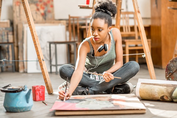 Female teenager painting on a canvas on the floor in an art studio